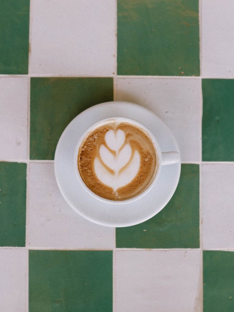Cappuccino with latte art on green checkerboard tiles