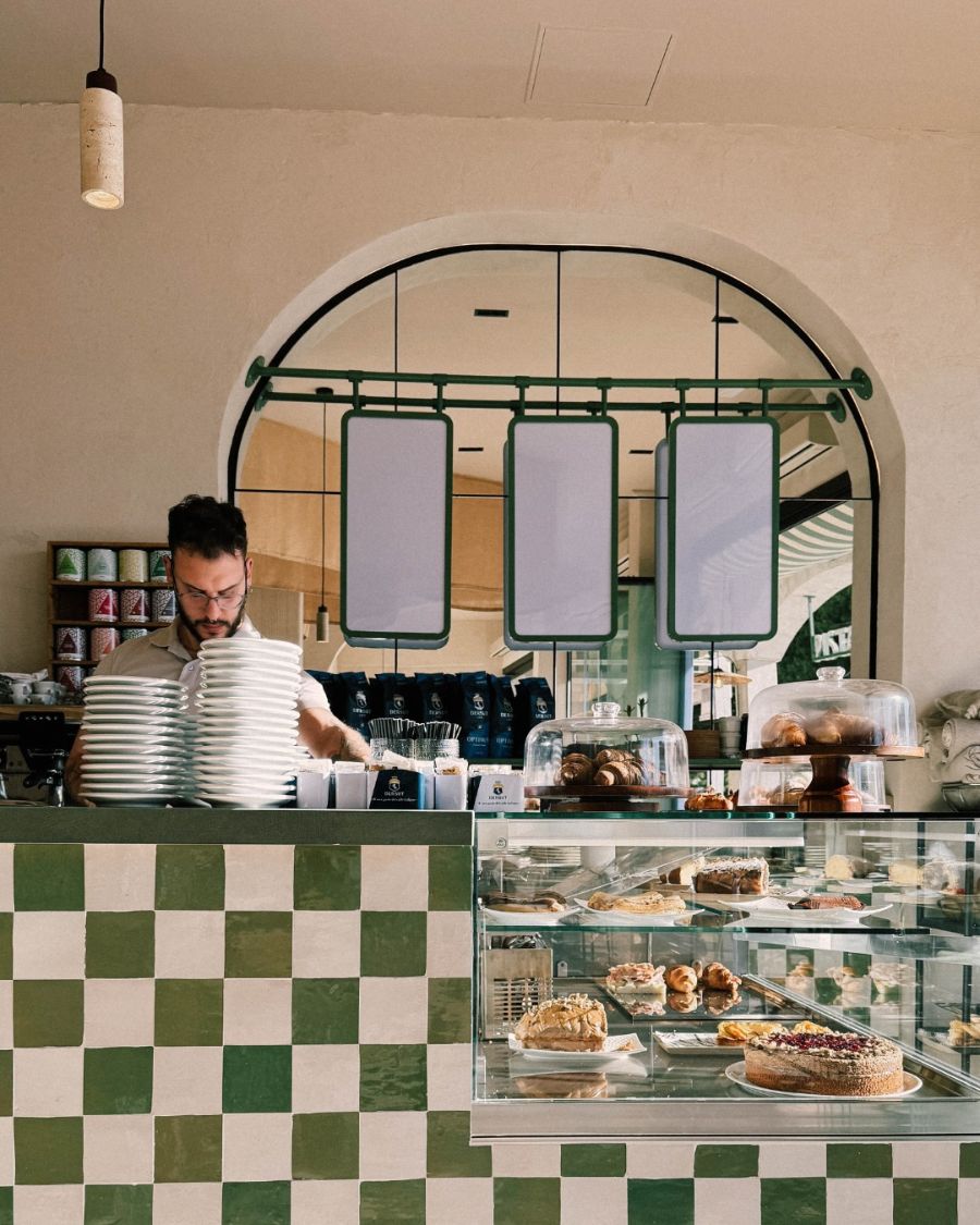 Barista at the counter beside the pastry and cake display case
