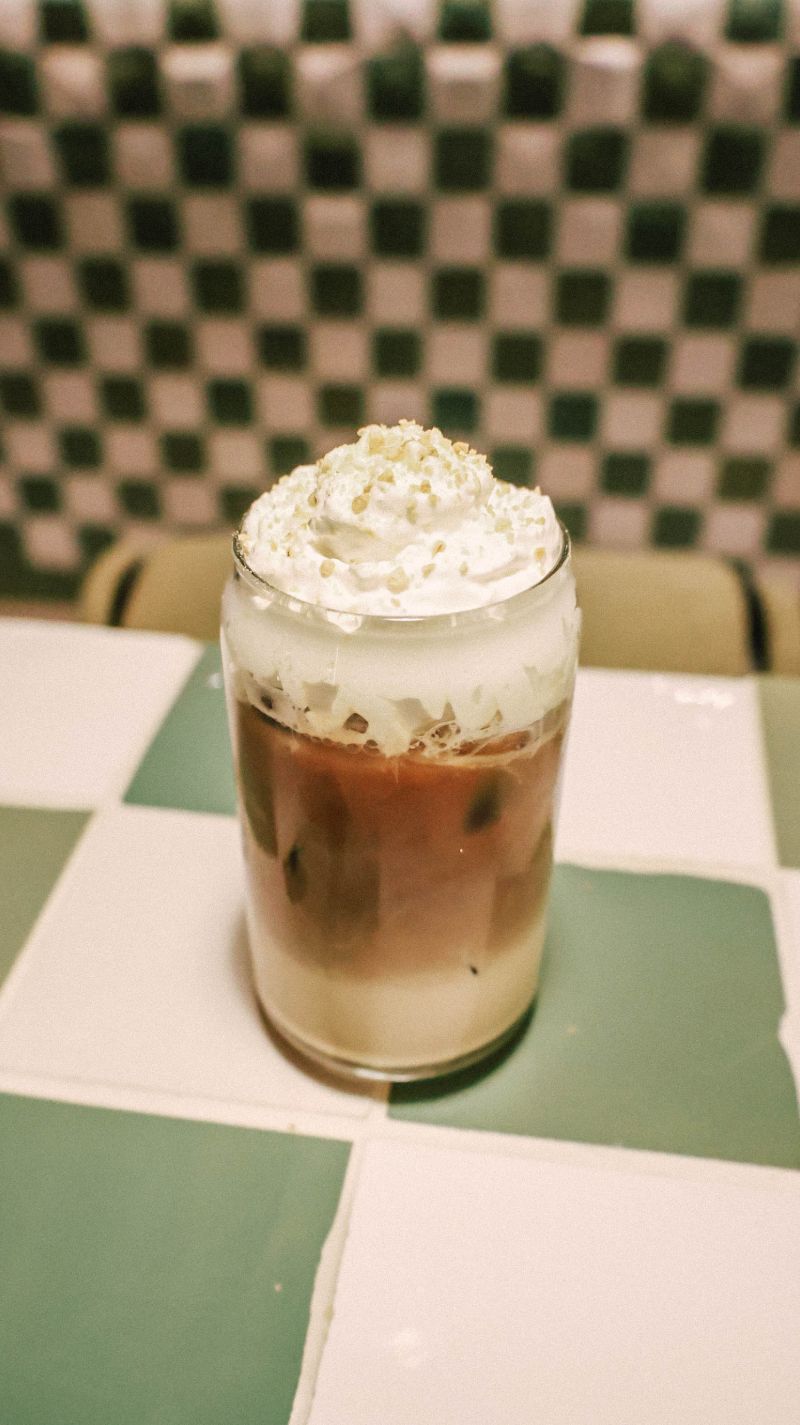 Iced pistachio latte topped with cream and crushed pistachio